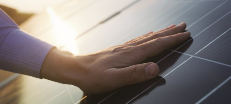 Close up of an young engineer hand is checking an operation of sun and cleanliness of photovoltaic solar panels on a sunset.Concept:renewable energy, technology,electricity,service, green,future